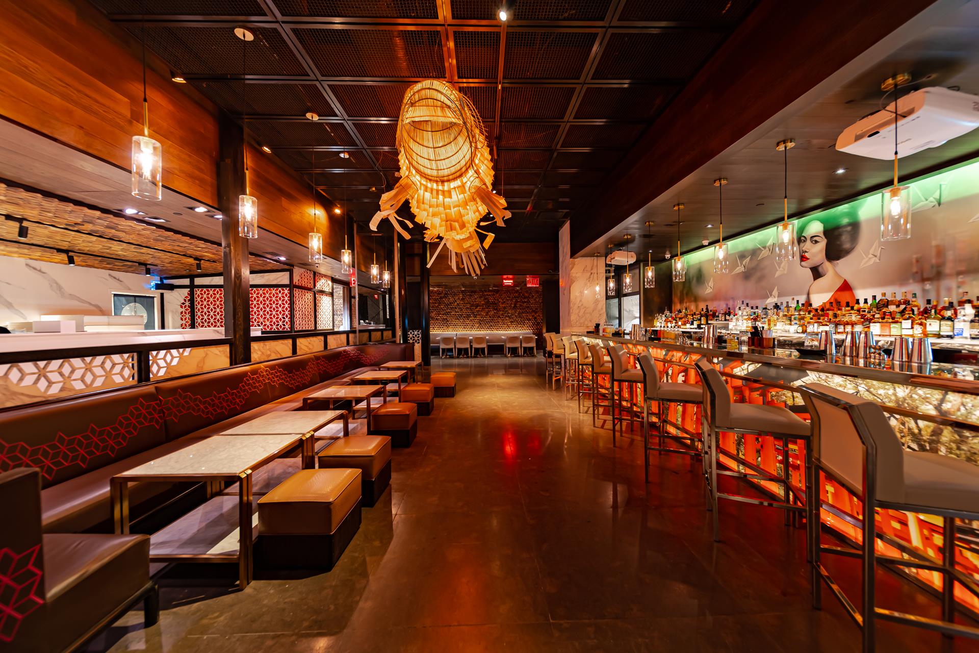 Fushimi Times Square's long dining room with red-lit booths, a glowing woven pendant lamp and a bar along the right wall