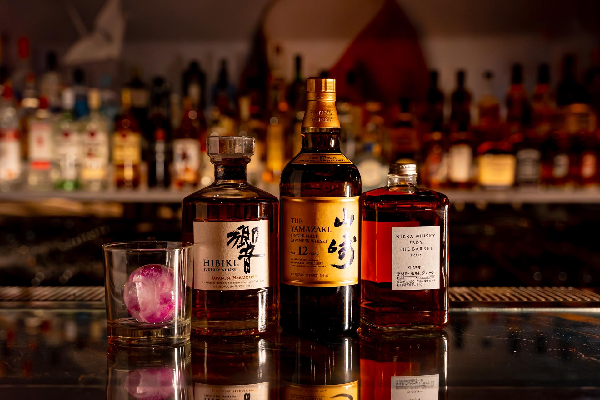 Bottles of Japanese whisky on the bar at Fushimi Times Square, with a lit back bar behind