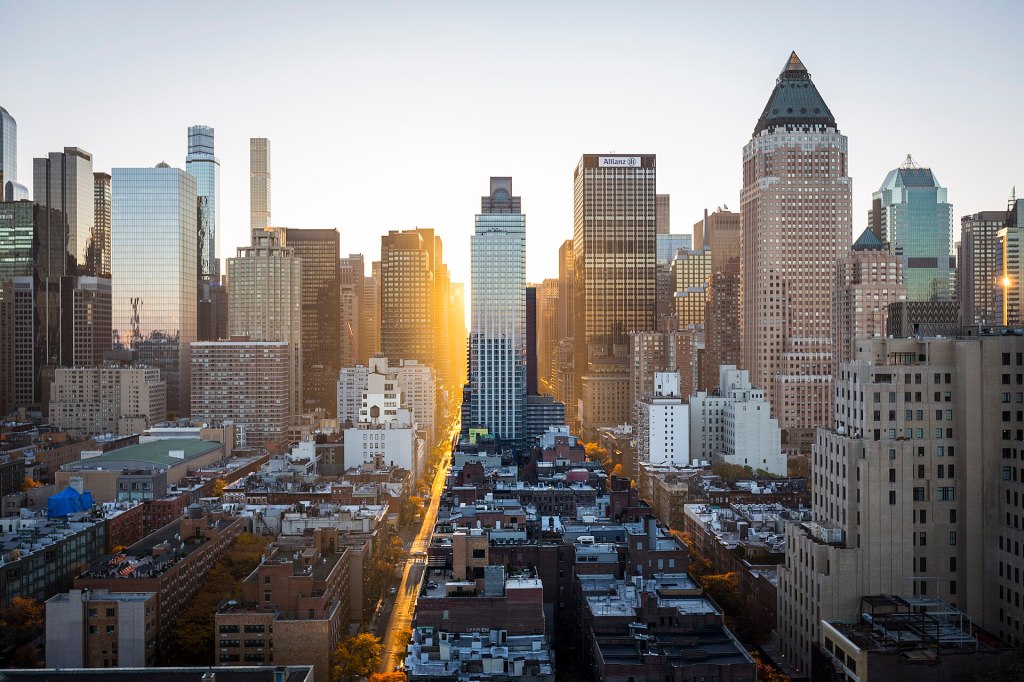 Sun rising between Manhattan skyscrapers, lighting up a New York street
