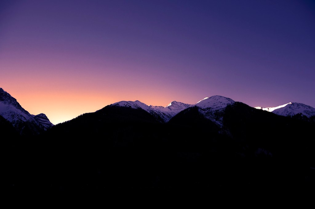 Snow-capped mountain summits glowing at sunrise