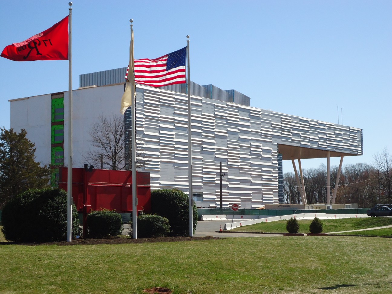 A modern university building on a green lawn with the American flag flying out front